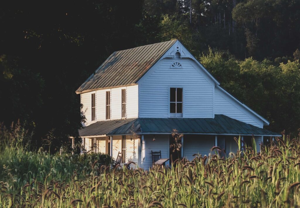 Old white farmhouse with corn fields.
