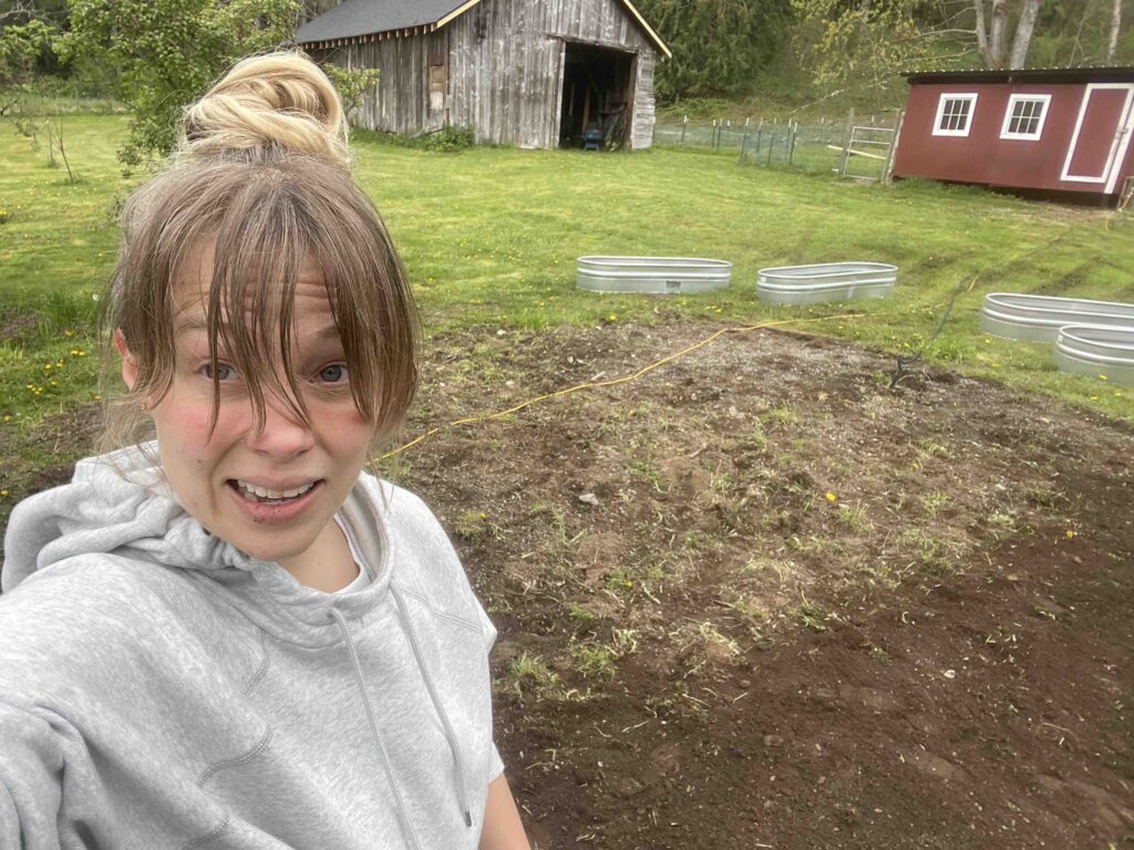 Photo of me standing in dirt patch of a garden with dirt on my face while I'm making a fun face. This is real farm life.