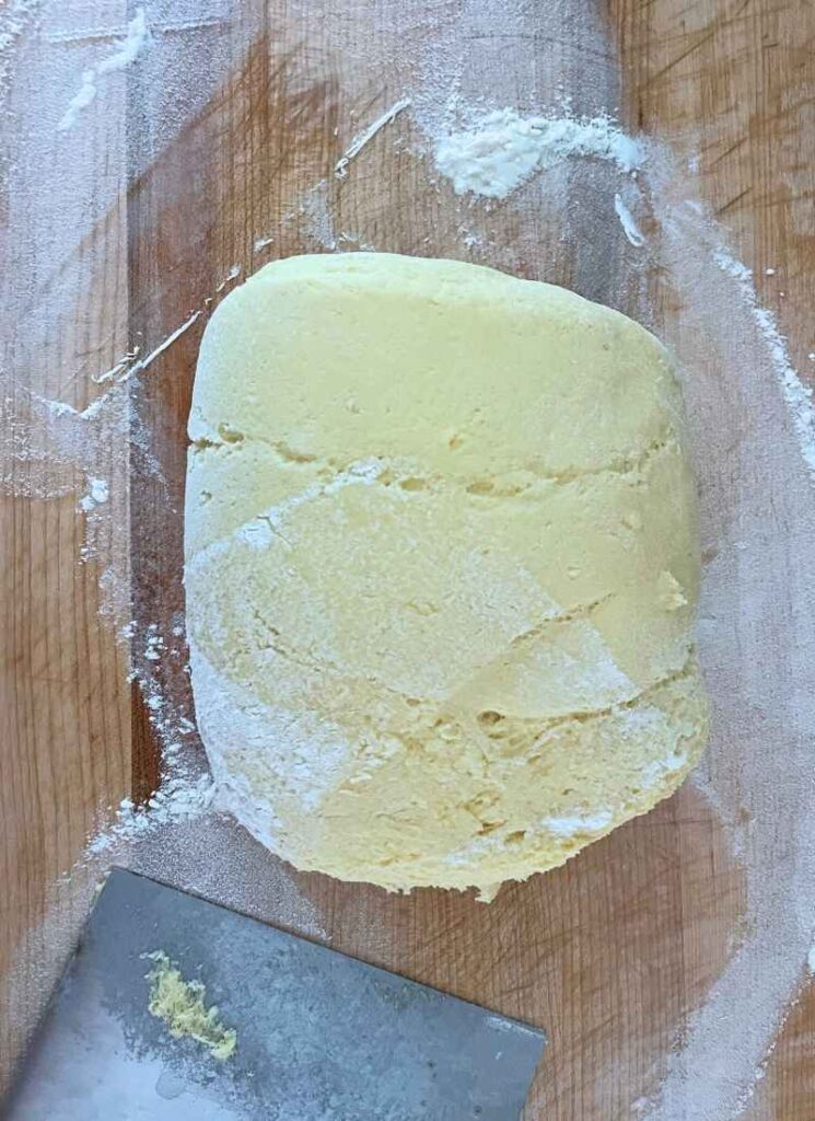 Brioche dough proofed and resting in a rolled ball on the countertop with some flour