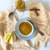 Bird's eye view of my traditional homemade cinnamon applesauce with a bowl and jar in view, plus the sliced lemon and cinnamon sticks.