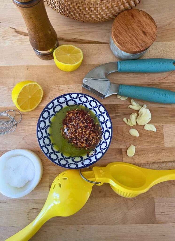 Top-down photo of fresh ingredients for marinade for the sheet pan corn and shrimp. Includes garlic, salt, olive oil, and chili peppers